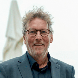 Tom Köhler, DIHZ, als Portrait, lachend mit zrezauselten lockigen Haaren