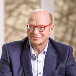 Walter Stuber im Portrait mit roter Brille und blauem Jacket.