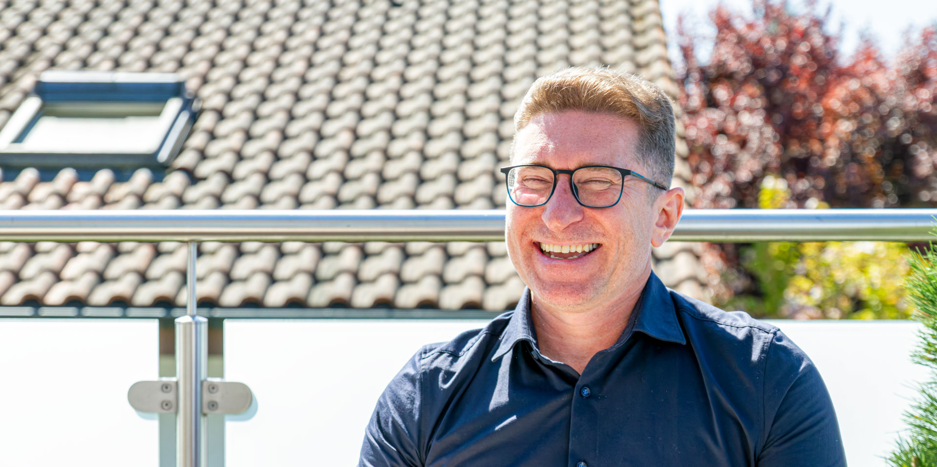 Andreas Ginger auf dem Balkon in der Sonne, lachend.