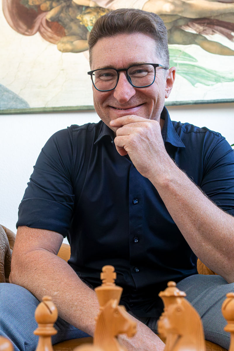 Andreas ginger lächelnd vor einem Schachbrett.